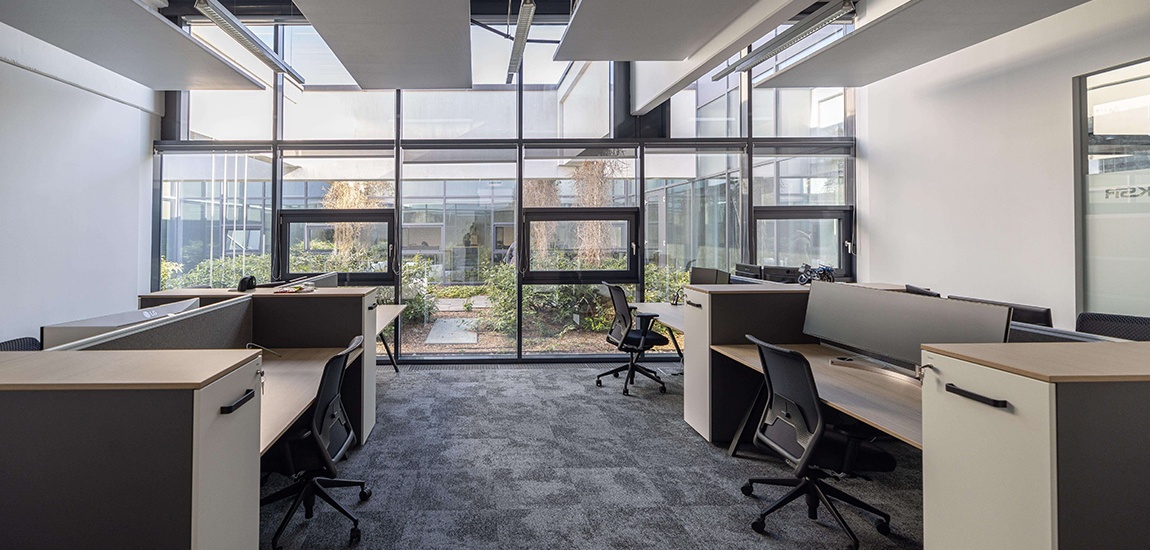 Modernes helles Büro mit Blick auf einen kleinen begrünten Innenhof.