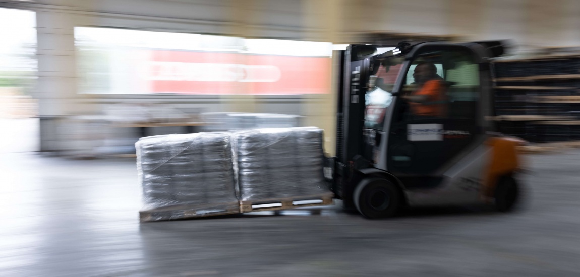 Gabelstaplerfahrer der zwei volle Paletten in einer Halle transportiert