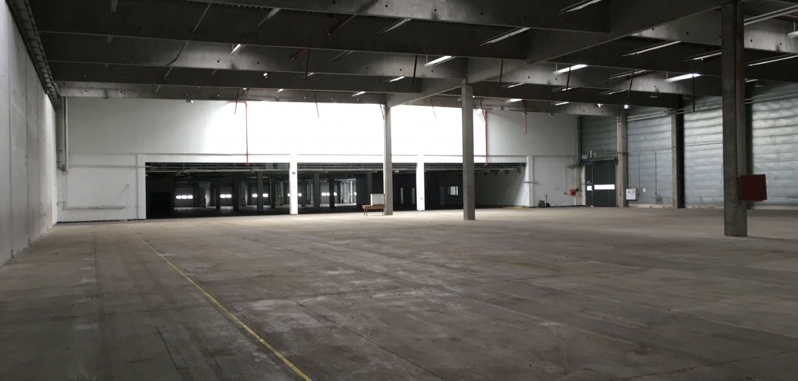 Innenansicht einer großen leeren Lagerhalle, Industrieboden und Verladebereich