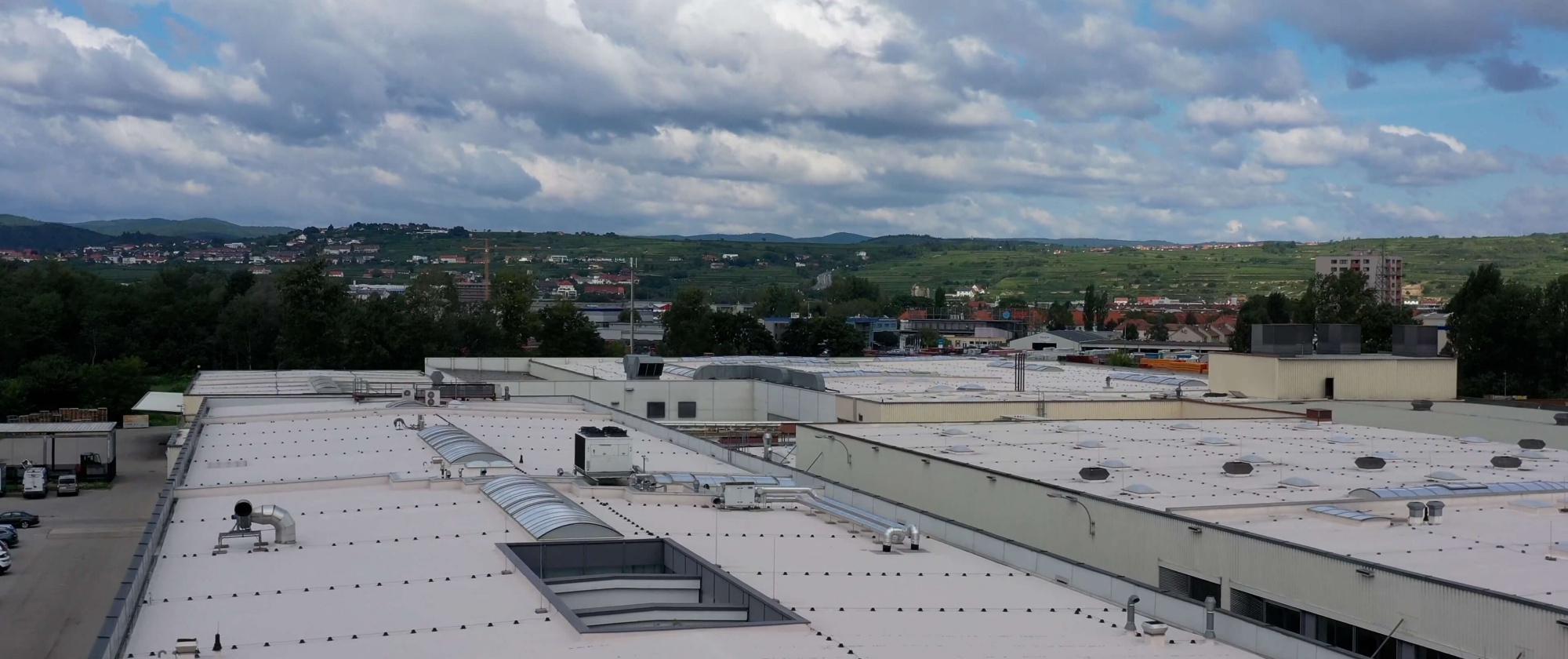 Blick über die ausgedehnten Dachflächen der DGK Hallen mit Aussicht auf Weinberge
