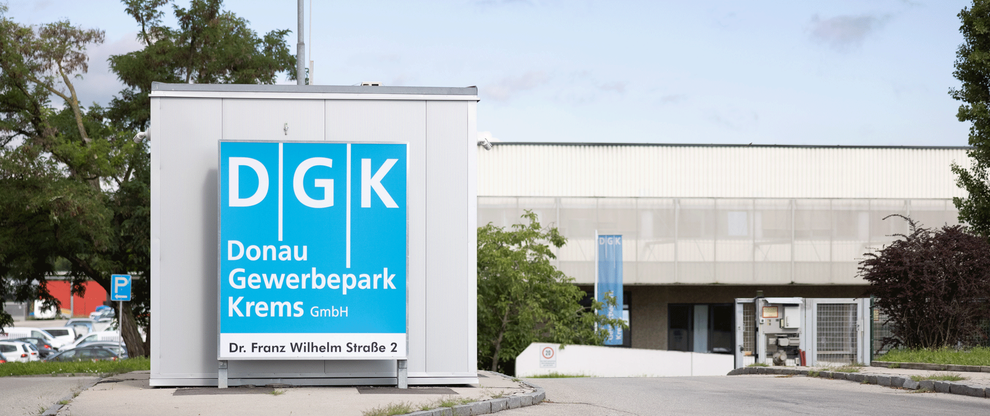 Einfahrtsbereich DGK Komplex mit blauem Firmenlogo und Straßennamen
